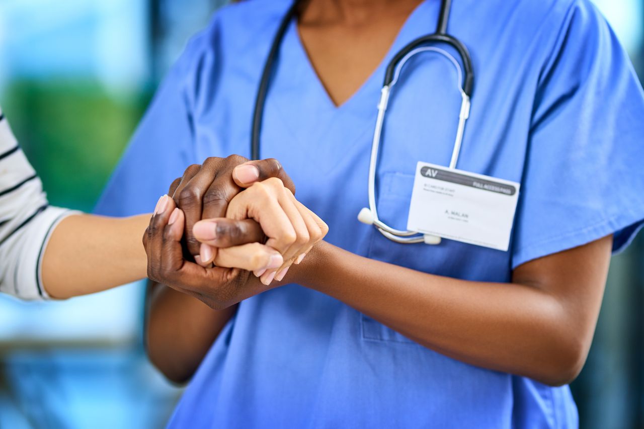 Une main réconfortante posée sur celle d'un patient en milieu hospitalier